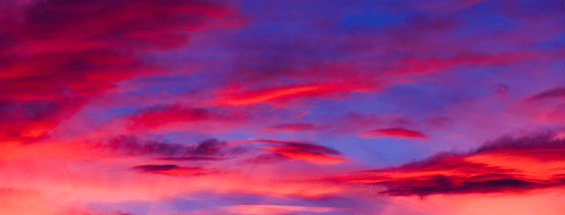 A view of the sky at sunset with bright pinks, oranges and blues.