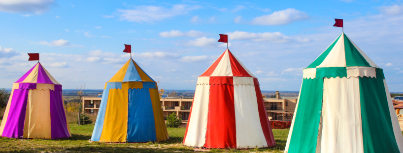 Three medieval-like tents sit on some grass