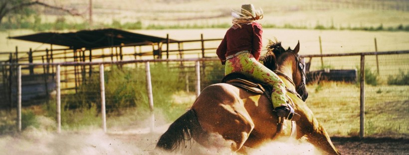 A woman with a cowboy hat on horseback