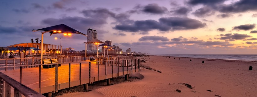 A lit boardwalk on a beach at night